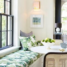 a white table sitting next to a window in a living room filled with green furniture