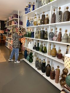 a little boy standing in front of shelves filled with vases