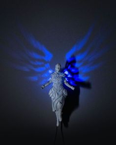 an angel statue with blue wings in the dark