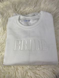 a white t - shirt with the word bride on it sitting on a furry surface