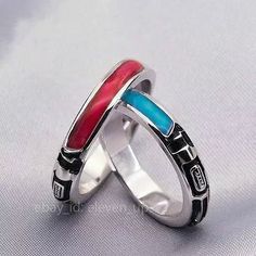 two silver rings with red and blue enamel inlays on each side, set against a white background