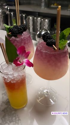 two glasses filled with drinks sitting on top of a white counter next to each other