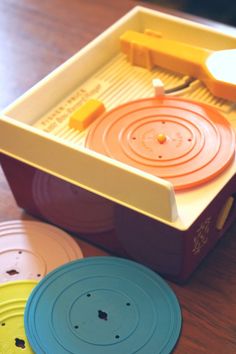 three different colored discs in a box on a wooden table with one disc missing the lid