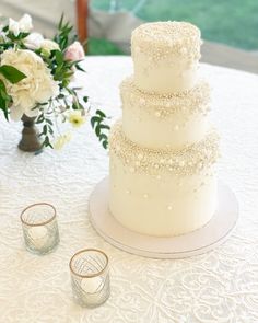 a three tiered wedding cake sitting on top of a table next to two glasses