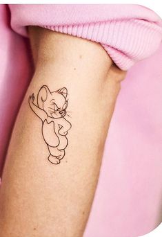 a cat tattoo on the arm of a woman's left arm, with a pink sweater