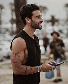 a man with tattoos on his arm holding a cell phone and looking off to the side