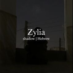 a person sitting on the ground in front of a building at night with the words zylia shadow hebrew