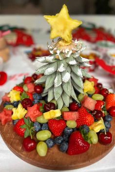 a wooden plate topped with fruit and a pineapple shaped christmas tree on top of it