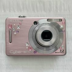 a pink camera sitting on top of a white blanket