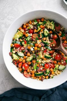 a white bowl filled with vegetables on top of a blue cloth next to a wooden spoon