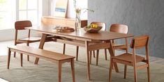 a wooden table with four chairs and a bowl of fruit on the dining room table