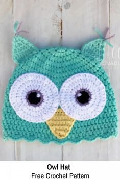 crocheted owl hat with big eyes on white wooden background for baby or toddler