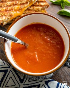 a bowl of tomato soup with grilled cheese on the side