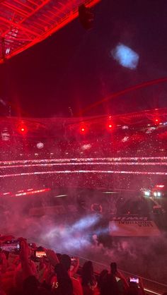 a stadium filled with lots of people watching something on the stage and fireworks in the air