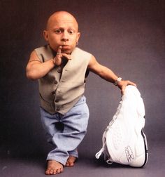 a bald man holding a baseball glove in front of his face while standing next to a bag