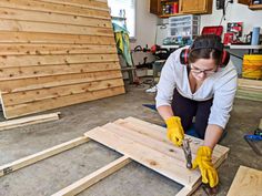 a woman working on wood in a garage with headphones and work gloves over her face