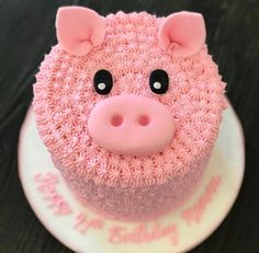 there is a pink cake with a pig face on it