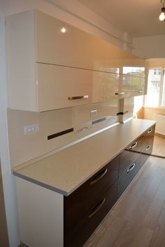 an empty kitchen with wooden floors and white counter tops, is pictured in this image