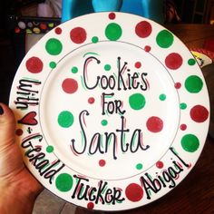 a plate with the words cookies for santa written on it is being held by someone