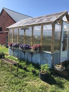 an old greenhouse with potted plants on the side and flowers growing in pots next to it