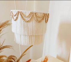 a white chandelier with beads hanging from it's sides next to a potted plant