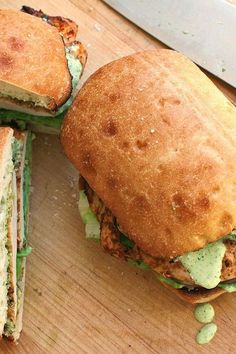 two sandwiches cut in half sitting on top of a cutting board next to a knife