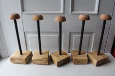 four wooden pieces with black handles are lined up in front of a white door,