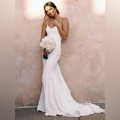 a woman in a white dress is posing for the camera and holding a bridal bouquet