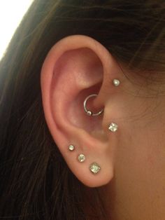 a woman's ear with three different piercings