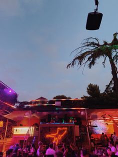 a group of people standing around in front of a building at night with lights on