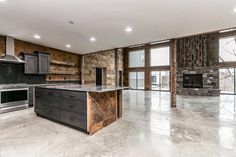 an empty kitchen and living room in a large house with stone walls, flooring and windows