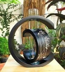 a vase sitting on top of a wooden table next to potted plants and greenery