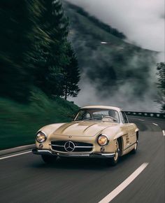 an old car driving down the road with fog in the background