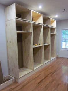 an empty room with wooden shelves in the middle and hard wood flooring on the other side