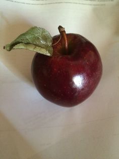 an apple with a green leaf on it sitting on a white tablecloth covered surface