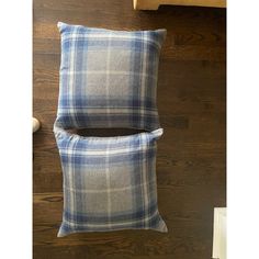 two blue and white plaid pillows sitting on top of a wooden floor