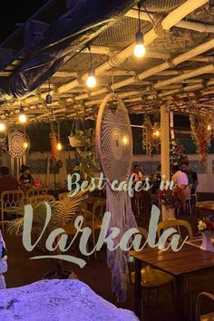 an outdoor restaurant with lights and decorations on the roof, along with people sitting at tables