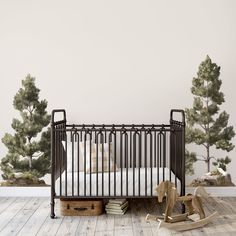 a baby's room with a crib, rocking horse and pine trees on the wall