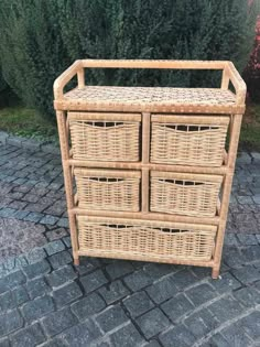 four wicker baskets are stacked on top of each other in front of some bushes