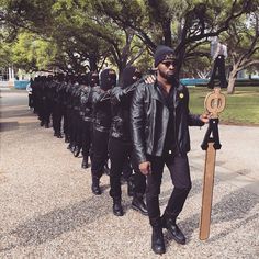 a man in black jacket holding up a wooden sign next to other men wearing leather jackets