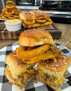 three hamburgers stacked on top of each other in front of some pretzels