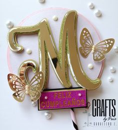 a close up of a cake topper with butterflies and the letter m on it