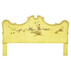 a yellow headboard with flowers and birds painted on the top, sitting against a white background