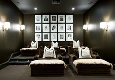 a home theater with brown couches and pictures on the wall behind them in a dark room