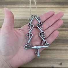 a hand holding a pair of scissors in the shape of a christmas tree with red stones