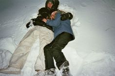 two people are laying in the snow together