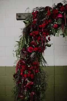 a cross decorated with red flowers and greenery