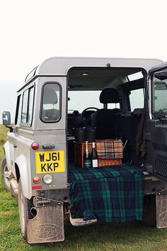 an old van is parked in the grass with its door open and luggage on it's back