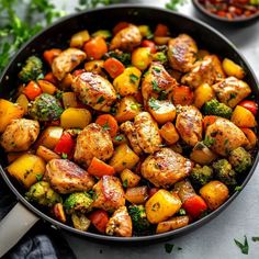 a skillet filled with chicken and veggies