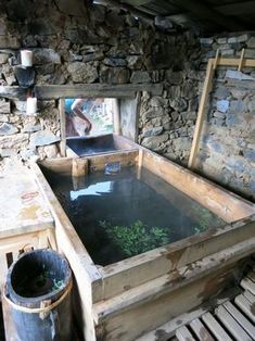 an old wooden trough filled with water next to a stone wall